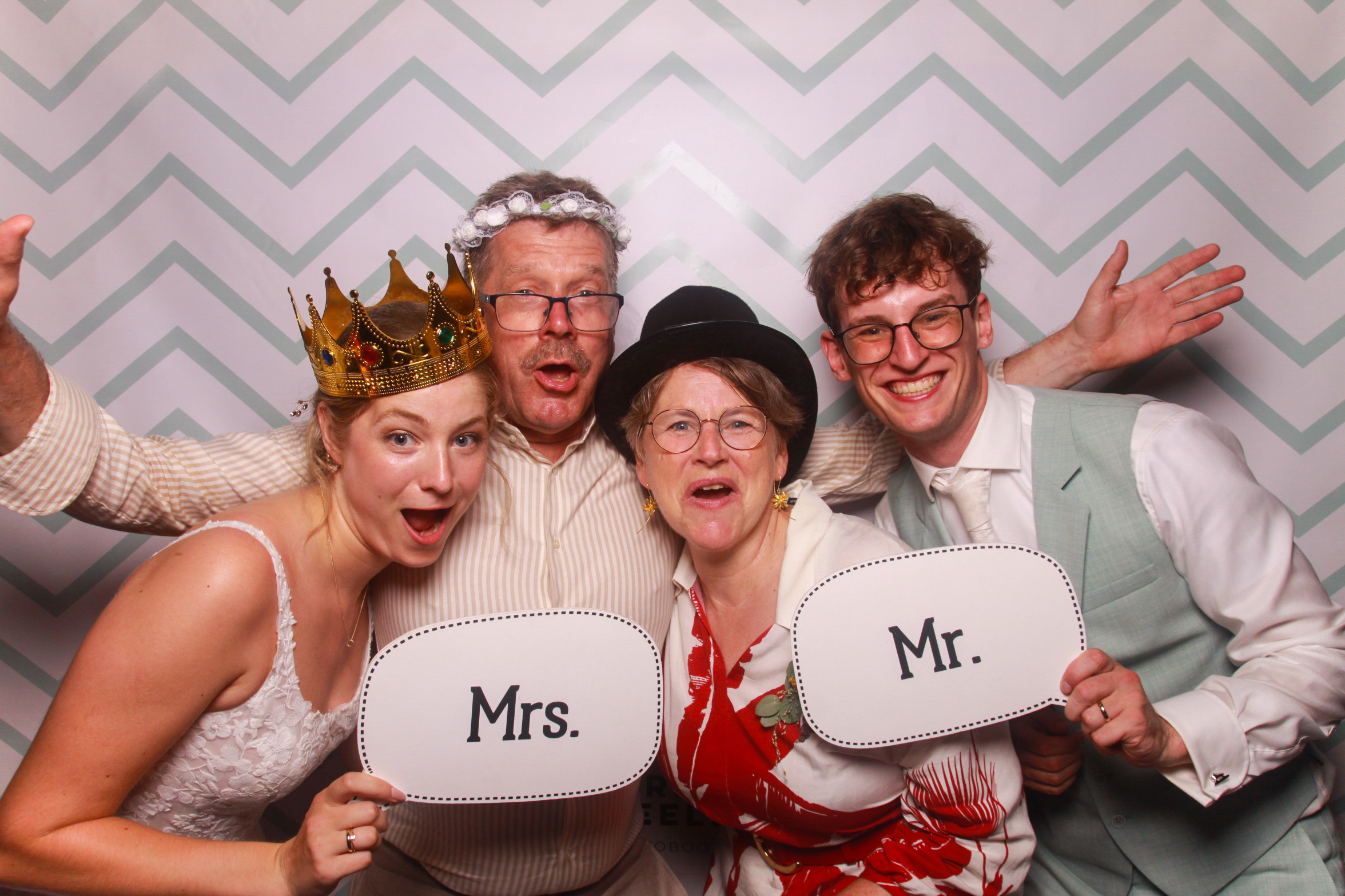 Bruidspaar en gasten met Mr. en Mrs. bordjes in de photobooth op een bruiloft