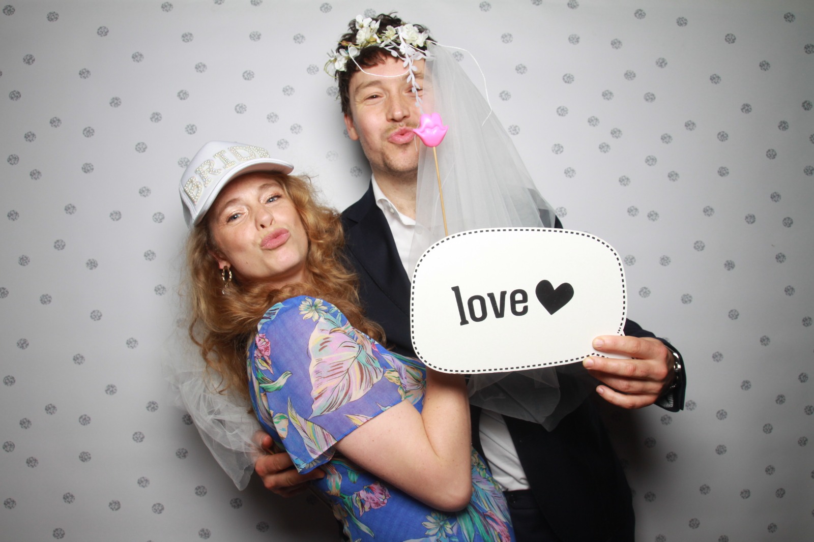Bruidspaar poseert met een love-bordje in de photobooth van Firma Beeld